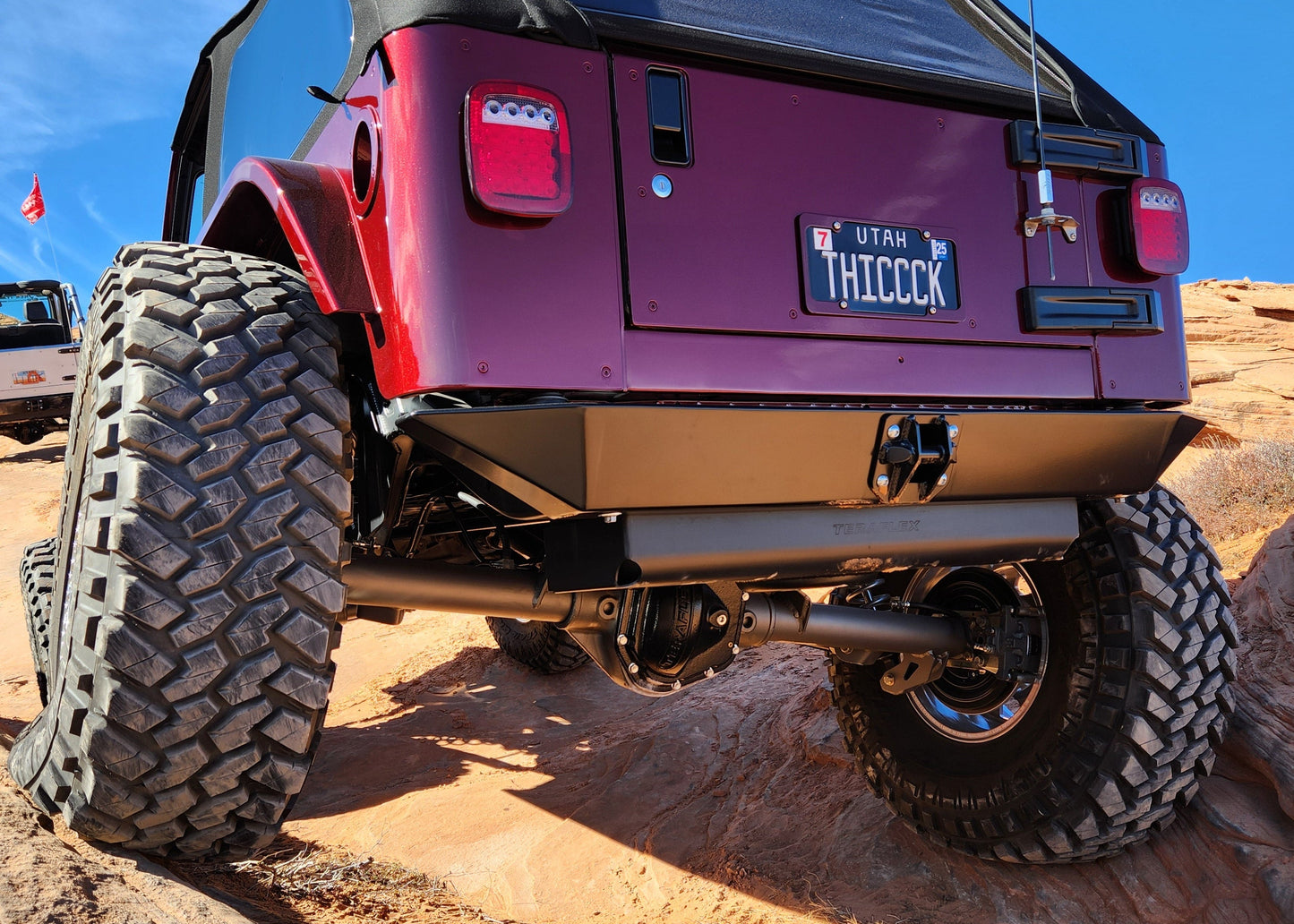 Purple Jeep with large off-road tires on a rocky desert landscape